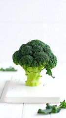 Fresh broccoli head on white cutting board