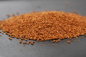 A Pile of Golden Brown Bee Pollen on Dark Table Top