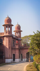 Historic red-brick building with ornate domed towers and arched gateway under a clear blue sky—ideal for architecture, heritage, and travel-themed stock photography.