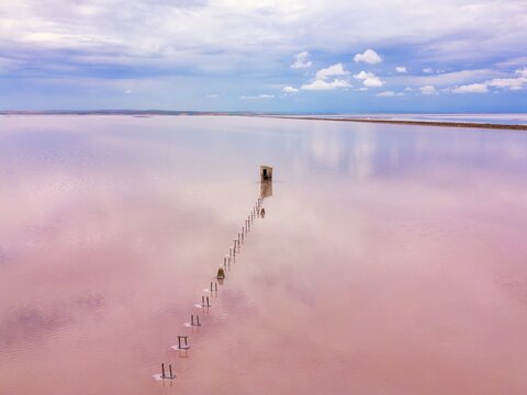 Drone view of pink salt lake Tuz in Turkey with old pier reflecting