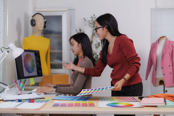 Fashion designers choosing colors for new clothes collection using color palettes and computer...