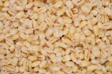 A dense full-frame shot of cooked, light brown pearl barley showcases its uniform texture and...