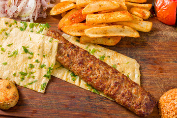 Traditional Adana kebab with fries, lavash, bulgur and onion salad