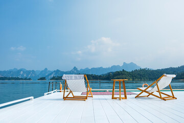 wooden beach chair and coffee table on white raft and swimming pool at waterfront of the open water...