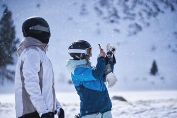 Sisters in ski gear taking photo with smartphone in snowy landscape