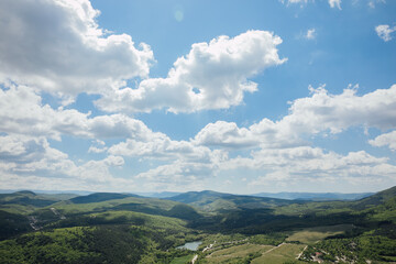 landscape on the mountains, green forest and blue sky with clouds