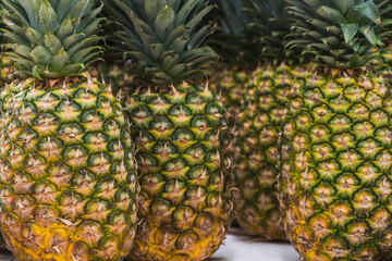 Fresh pineapples at supermarket with concept of rising food prices and cost of living.  Group of pineapples on display at grocery store, representing inflation and food affordability issues