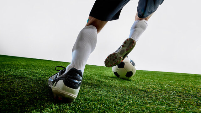Soccer player dribbling black and white ball on grass field in motion. Concept of team sports visuals, football ads, athlete training posters, physical education content.