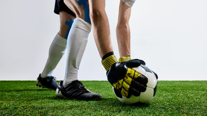Football player in gloves placing ball on field in cleats and tape. Concept of team coordination,...