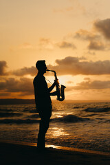 A beautifully detailed silhouette of a saxophonist playing music against a vibrant sunset at the beach