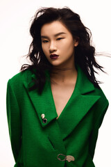 Stylish woman in a green coat with striking makeup.