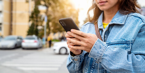 Casual woman using smartphone while standing on urban street