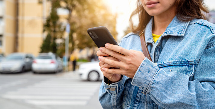 Casual woman using smartphone while standing on urban street