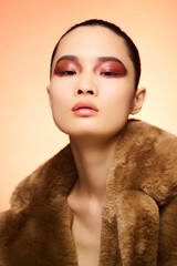 Portrait of a young woman with bold makeup and fur coat.