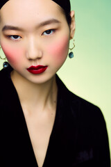 Young Asian female with bold makeup and earrings.