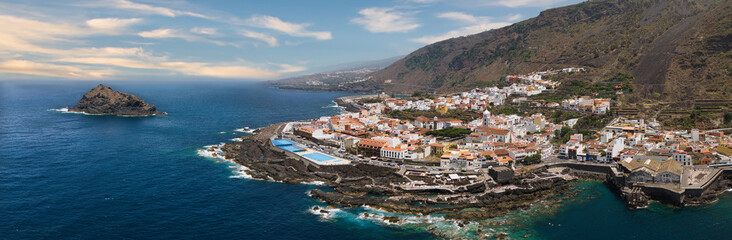 Aerial panoramic view of a town in Tenerife with natural swimming pools and the mountains in the...