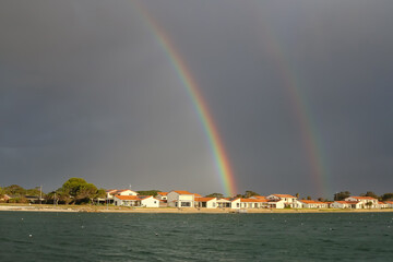 Double rainbow over waterfront houses after storm, Australia, dramatic sky and evening sunlight