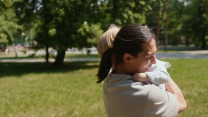 Joyful father tossing his little son in air and hugging him affectiuonately, spending time in park on summer day