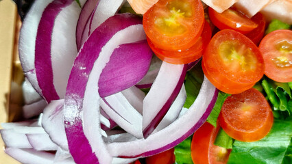 Close-up vibrant red onion slices and bright red cherry tomato halves, ready added fresh salad or other culinary creations.
