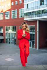 vertical Businesswoman walking and using smartphone in front of office building