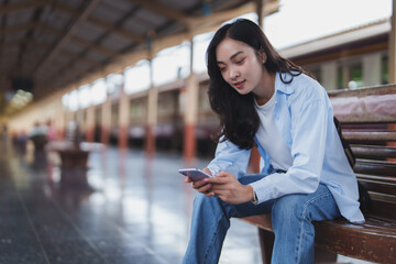 Young woman using smartphone while waiting at train station