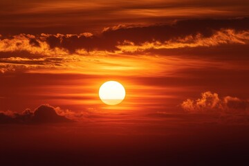 Obraz premium Aerial view of a vivid orange sunset casting warm light over the calm sea, with glowing reflections on the water surface and a tranquil horizon, capturing the serene beauty of nature from above