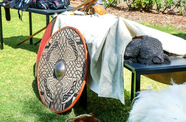 Decorated Viking shield with chainmail armor and medieval weapons displayed outdoors at reenactment...