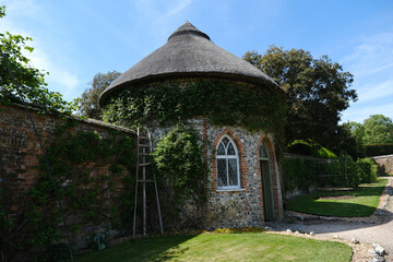 The circular flint Apple Store with thatched roof in West Dean Gardens.