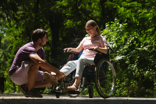 Man Assisting Woman in Wheelchair in a Peaceful Park