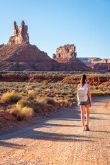 A woman is walking leisurely along a dirt road in the desert, Young Woman on Road in Valley of The...