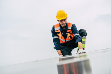 Worker installs solar panels on rooftop during overcast day in urban setting with safety gear and...