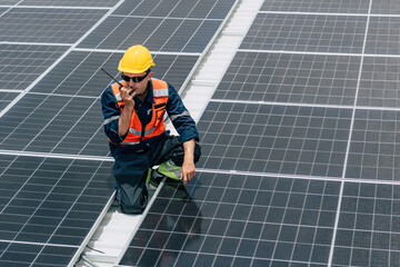 Worker communicates on a rooftop during solar panel installation in bright daylight