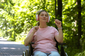 Woman Enjoying Music in Wheelchair in a Sunny Park Setting