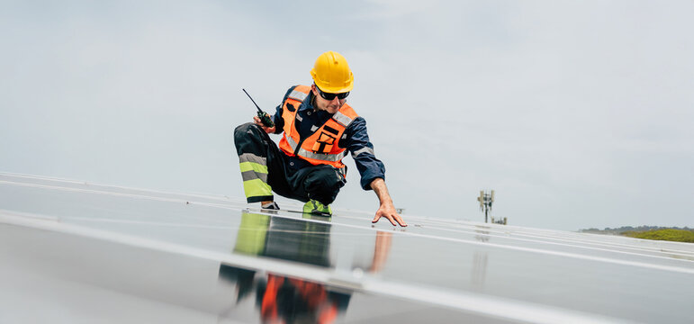 Worker inspects solar panels on a rooftop during daylight in a renewable energy project