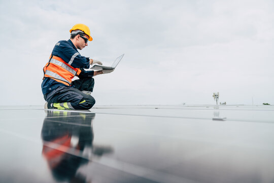 Worker analyzes solar panels at a renewable energy facility during daylight hours - Powered by Adobe