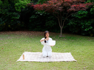 Chinese woman meditating with Tibetan singing bowl Outdoors. Yoga practice in sunny day. Spiritual...