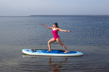 Sport woman doing yoga on sup board. A beautiful young woman relaxes on a SUP board. Standup...