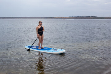 Woman on stand up paddle board. Woman practicing SUP yoga, meditating on a paddle board. Woman on...