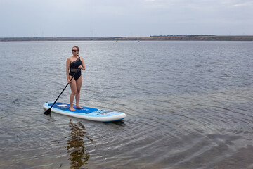 Stand up paddle boarding on a quiet sea with warm summer sunset colors