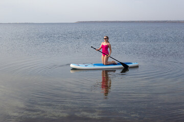 Young woman on stand up paddle board. Stand up paddle boarding on a quiet lake
