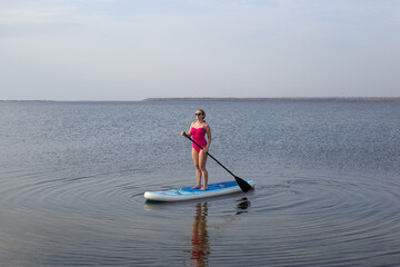 Woman on stand up paddle board. Woman practicing SUP yoga, meditating on a paddle board. Woman on...