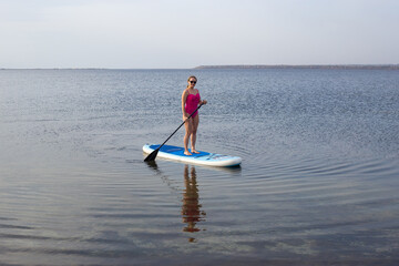 Sport woman on sup board. A beautiful young woman relaxes on a SUP board. Standup paddleboarding