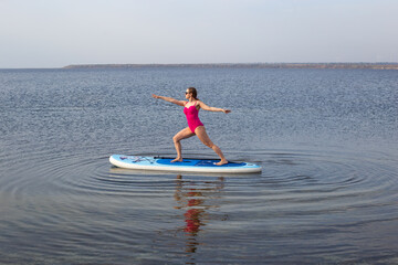 Girl on stand up paddle board. Woman practicing SUP yoga, meditating on a paddle board. Woman on...