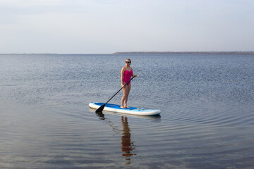 Sport woman on sup board. A beautiful young woman relaxes on a SUP board. Standup paddleboarding