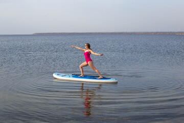 Woman practicing SUP yoga, meditating on a paddle board. Woman on sup board.