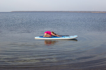 Woman doing yoga on Stand Up Paddle Board in Calm Lake. Summer Water Sport, Outdoor Adventure,...