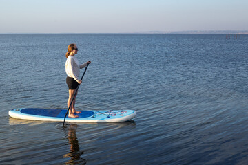 Sport woman on sup board. A beautiful young woman relaxes on a SUP board. Standup paddleboarding