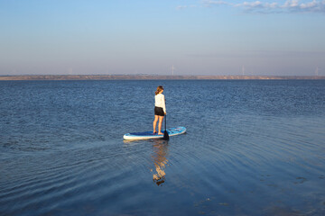 Woman on sup board. A beautiful young woman relaxes on a SUP board. Standup paddleboarding