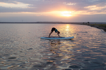 woman doing yoga on sup board at sunset. outdoor summer activity. Sup yoga. Social Distancing. copy...