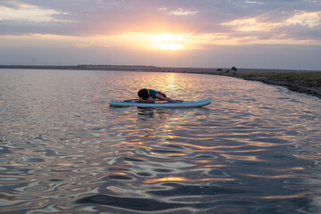 Girl on stand up paddle board. Woman practicing SUP yoga, meditating on a paddle board. Woman on...